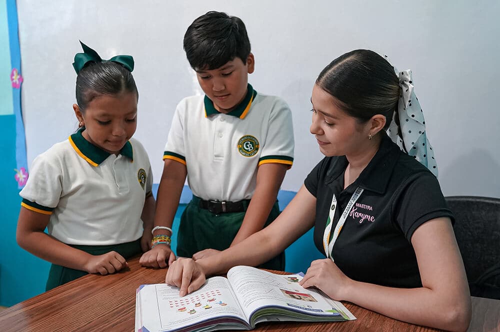 Maestra con dos alumnos de primaria — atención personalizada en Colegio Bambinos